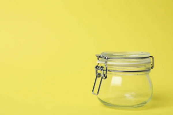 Frasco de vidro vazio fechado no fundo amarelo claro, espaço para tex — Fotografia de Stock