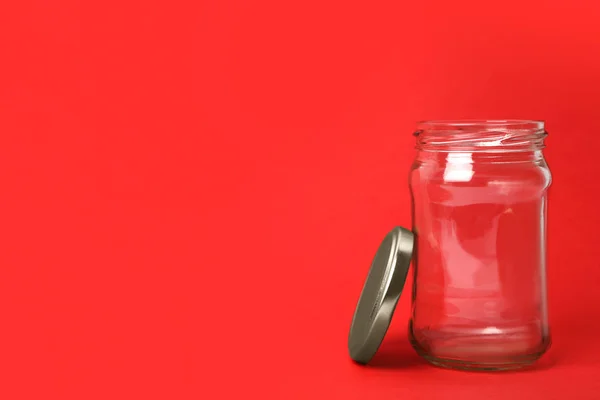 Abrir frasco de vidro vazio no fundo vermelho, espaço para texto — Fotografia de Stock