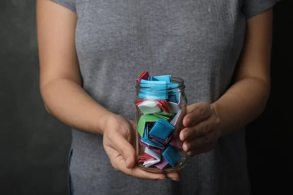 Vrouw met glazen pot met kleurrijke papieren stukken, close-up op h — Stockfoto