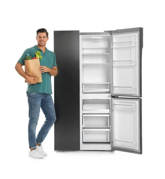 Человек Пакетом Продуктов Рядом Открытым Пустым Холодильником Белом Фоне — стоковое фото