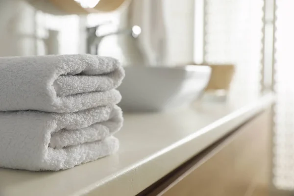 Pilha de toalhas limpas na bancada no banheiro. Espaço para texto — Fotografia de Stock