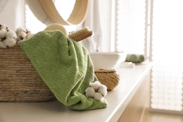 Proutěný koš s čistým ručníkem, masážním štětcem a bavlněnými květy — Stock fotografie