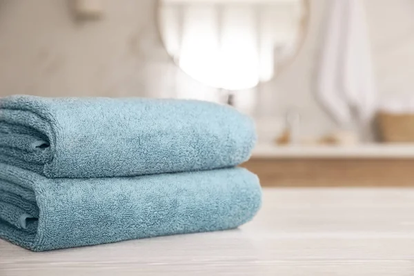 Pila di asciugamani puliti su tavolo di legno bianco in bagno. Spazio f — Foto Stock