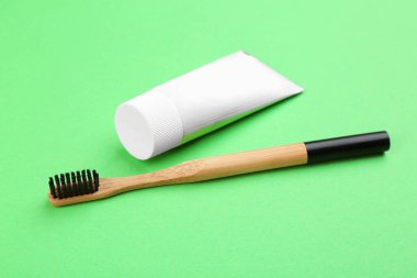 Yeşil arka planda doğal bambu diş fırçası ve yapıştırıcı.