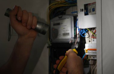 Fenerli elektrikçi içeride elektrik panelini tamir ediyor, yakın plan.