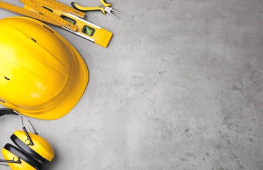 Gri zemin üzerinde farklı inşaat araçları olan düz bir kompozisyon. Metin için boşluk