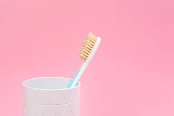 Natural bristle toothbrush in holder on pink background. Space f