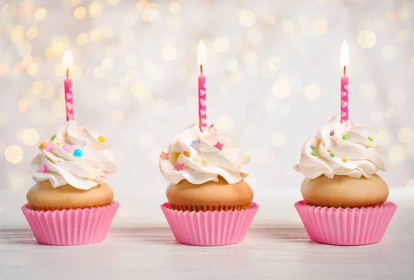 Cupcakes de aniversário com velas na mesa de madeira branca contra blu — Fotografia de Stock