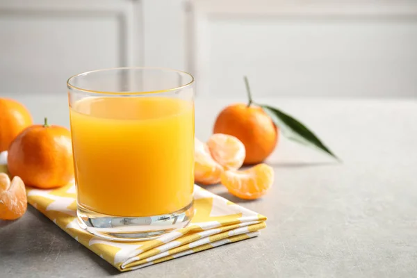 Vaso de jugo fresco de mandarina y frutas sobre mesa gris claro. S — Foto de Stock