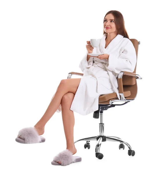 Jovem mulher em roupão de banho com xícara de bebida no fundo branco — Fotografia de Stock
