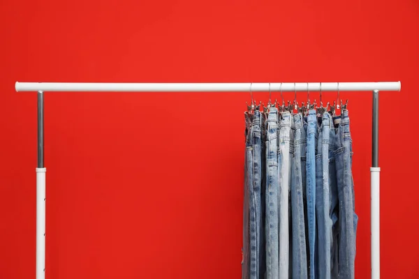 Scaffale con eleganti jeans su sfondo rosso — Foto Stock