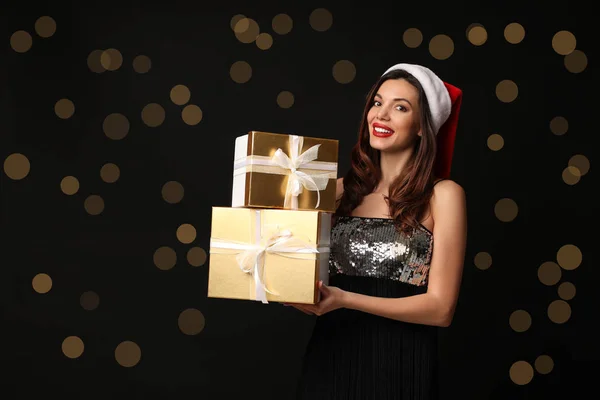 Güzel bir kadın Noel Baba şapkası takıyor ve siyah hediyeler takıyor. — Stok fotoğraf