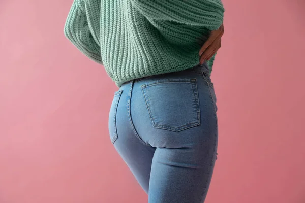 Vrouw in jeans op roze achtergrond, close-up — Stockfoto