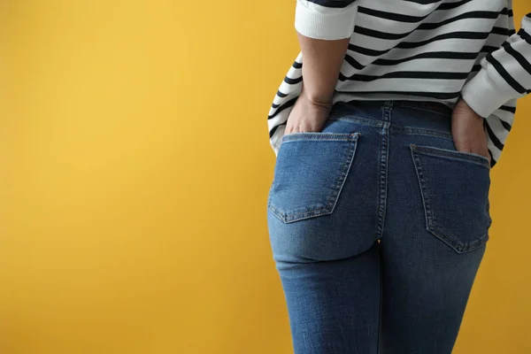 Mujer con jeans sobre fondo amarillo, primer plano. Espacio para tex —  Fotos de Stock