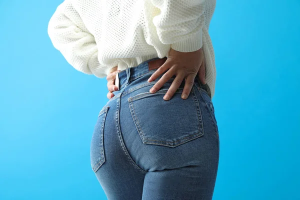 Vrouw draagt jeans op blauwe achtergrond, close up — Stockfoto