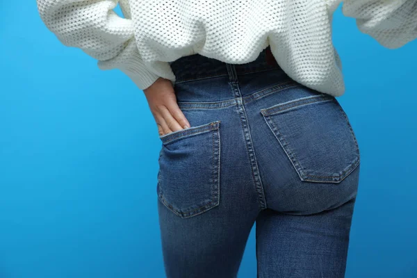 Vrouw draagt jeans op blauwe achtergrond, close up — Stockfoto