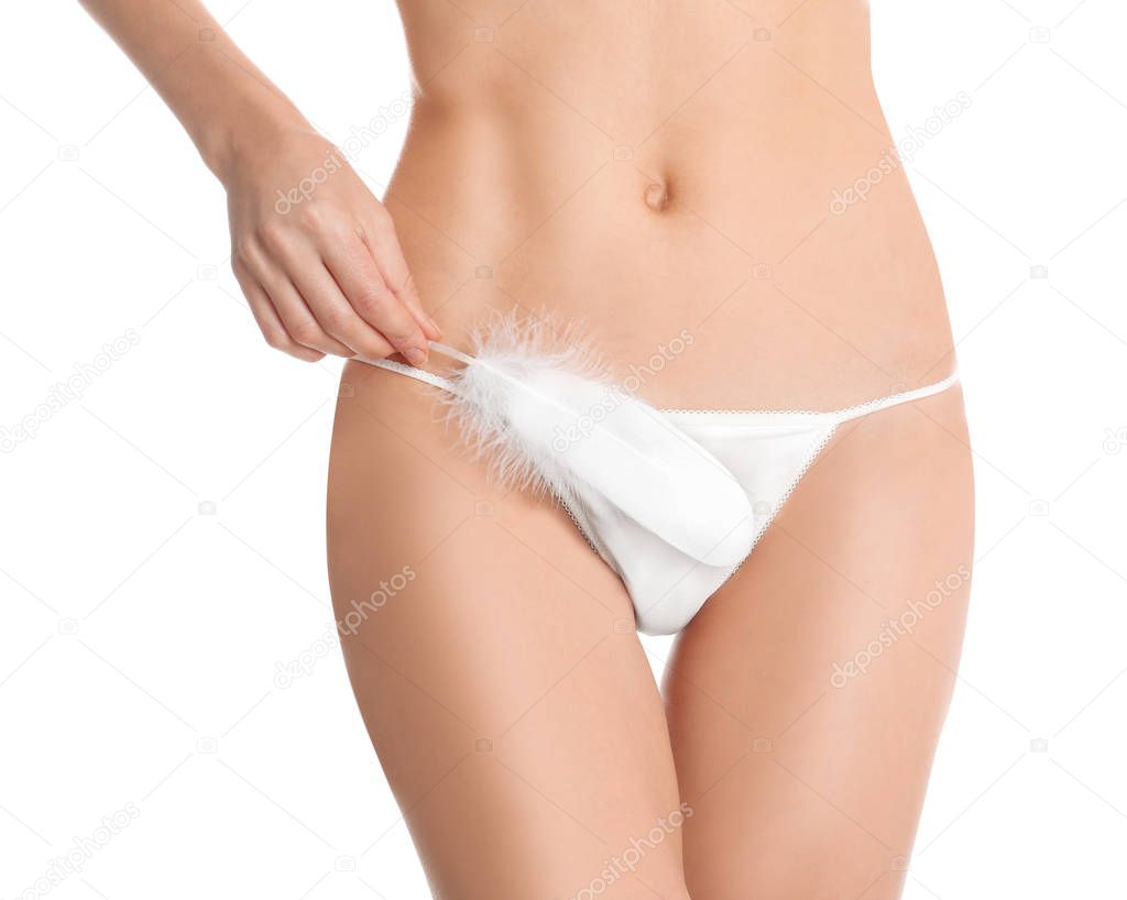 Woman with feather showing smooth skin after Brazilian bikini epilation on white background, closeup. Body care concept