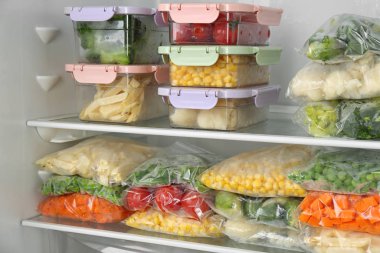 Plastic bags and containers with different frozen vegetables in refrigerator clipart