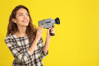 Sarı arka koltukta klasik video kamerası olan güzel genç bir kadın.