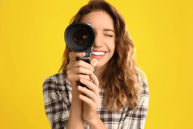 Sarı B 'ye karşı klasik video kamerası olan güzel genç bir kadın.