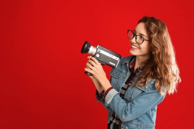 Red Backgroun 'da eski model video kameralı güzel genç bir kadın.