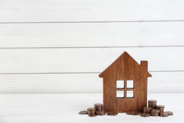 Ev modeli ve paralar beyaz ahşap masada. Metin için boşluk