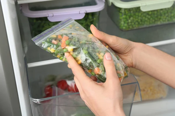 Mujer Poniendo Bolsa Plástico Con Verduras Congeladas Refrigerador Primer Plano — Foto de Stock