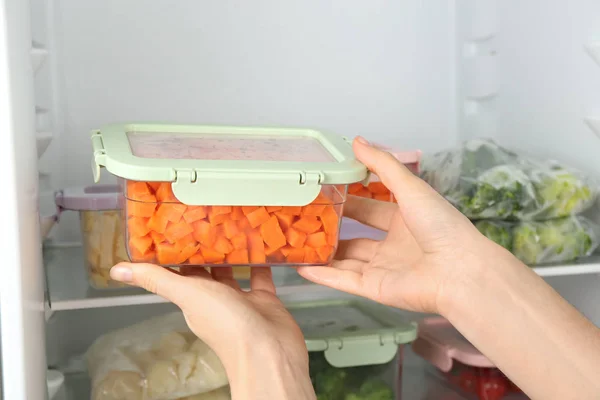 Mujer Poniendo Recipiente Con Zanahoria Refrigerador Con Verduras Congeladas Primer —  Fotos de Stock
