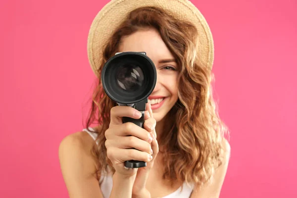 Mulher bonita usando câmera de vídeo vintage contra carmesim — Fotografia de Stock