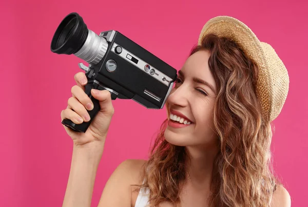 Belle jeune femme utilisant une caméra vidéo vintage sur fond cramoisi — Photo