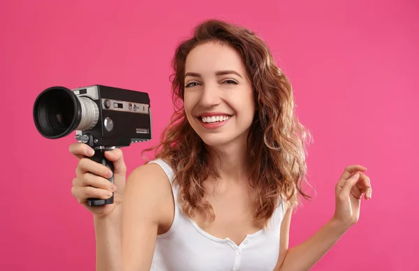 Mooie jonge vrouw met vintage video camera op crimson backg — Stockfoto