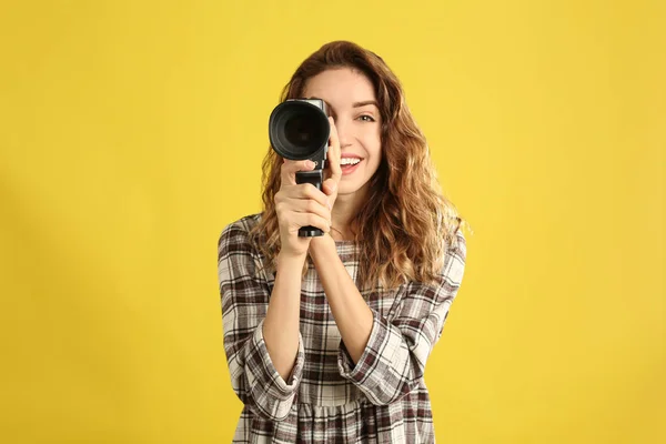 노란색 배경에 빈티지 비디오 카메라를 단 아름다운 젊은 여성 — 스톡 사진