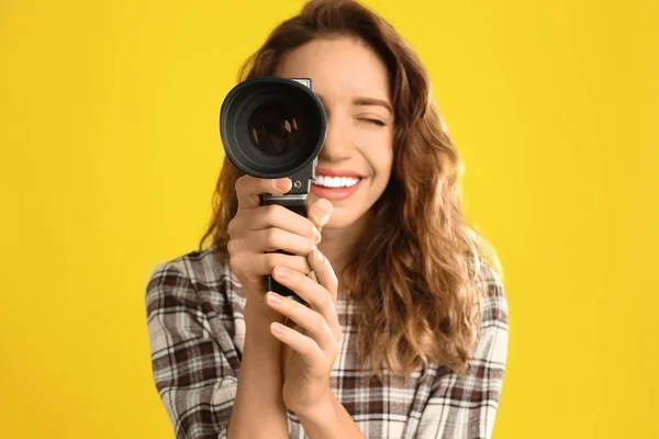 Mooie jonge vrouw met vintage video camera tegen geel b — Stockfoto