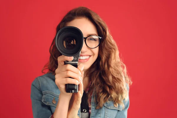 Mulher bonita com câmera de vídeo vintage contra costas vermelhas — Fotografia de Stock