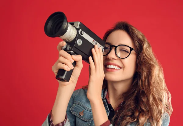 Mooie jonge vrouw met vintage video camera op rode backgroun — Stockfoto