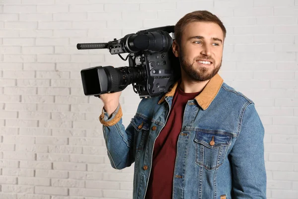 Bediener mit professioneller Videokamera in der Nähe der weißen Ziegelwand — Stockfoto