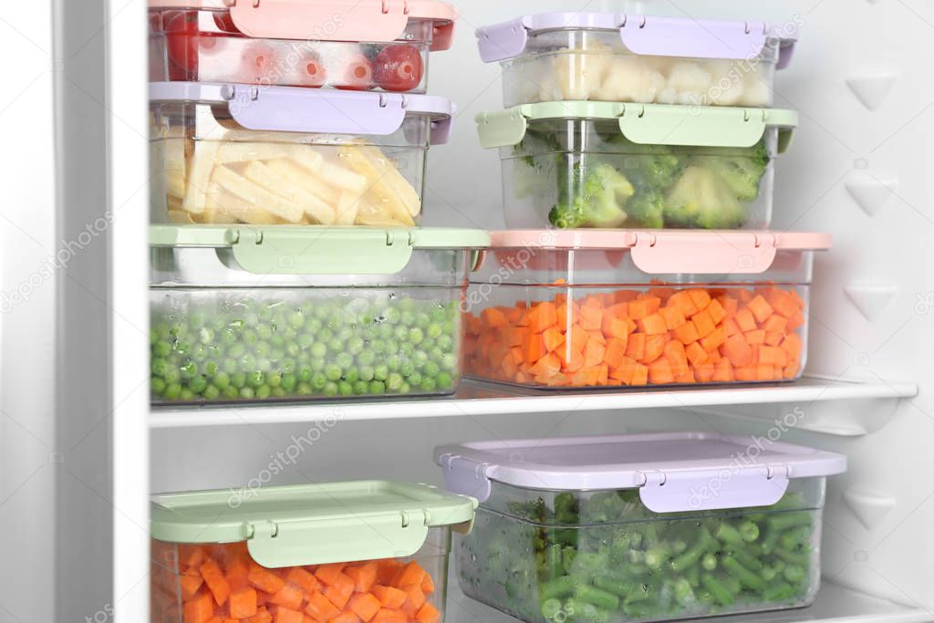 Containers with different frozen vegetables in refrigerator