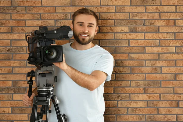 Opérateur avec caméra vidéo professionnelle près du mur de briques — Photo