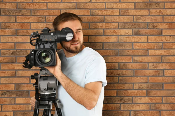 Opérateur avec caméra vidéo professionnelle près du mur de briques, espace f — Photo