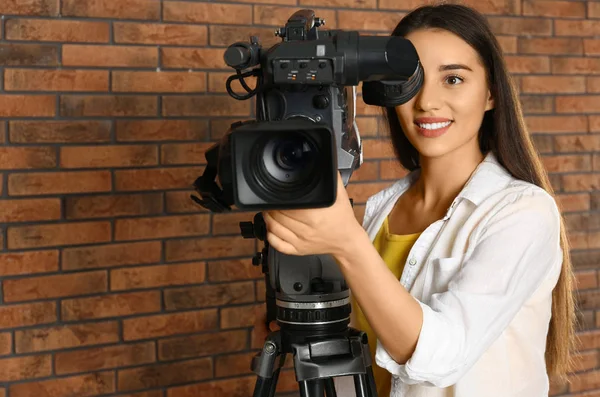 Opérateur avec caméra vidéo professionnelle près du mur de briques — Photo