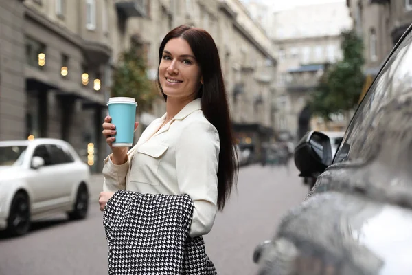 Vacker kvinna i snygg kostym med kopp kaffe på city stree — Stockfoto