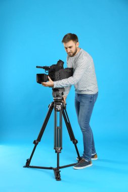 Mavi arkaplanda profesyonel video kamerası olan operatör