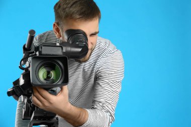 Mavi arkaplanda profesyonel video kamerası olan operatör