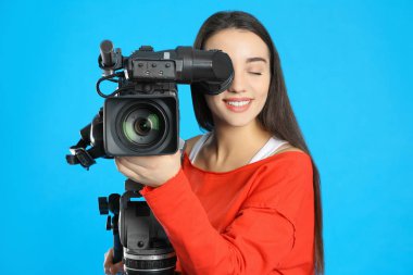 Mavi arkaplanda profesyonel video kamerası olan operatör