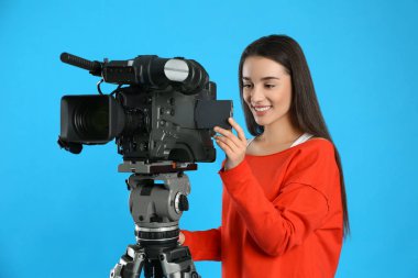Mavi arkaplanda profesyonel video kamerası olan operatör