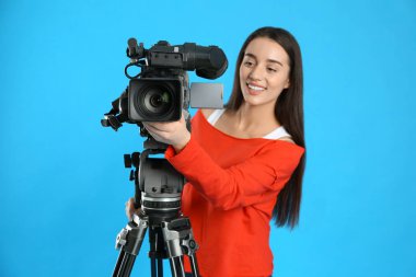 Mavi arkaplanda profesyonel video kamerası olan operatör