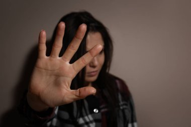 Bej duvarın yanında duran tacize uğramış genç bir kadın, eline odaklan. Aile içi şiddet kavramı