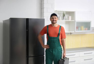 Buzdolabının yanında alet çantası olan erkek teknisyen.