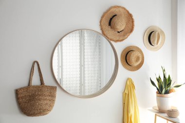 Lamba odasındaki beyaz duvarda ahşap çerçeveli yuvarlak ayna.