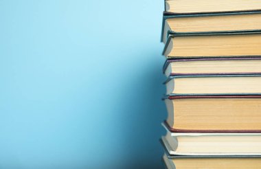 Açık mavi arkaplan üzerine ciltli kitap yığını, metin için boşluk
